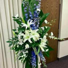 Tall white and blue floral standing spray on an easel