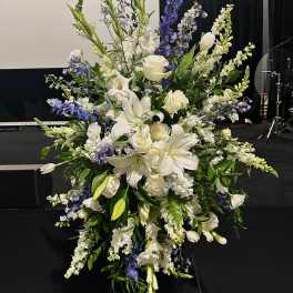 Tall white and blue floral standing spray on an easel