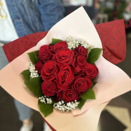 Bouquet of red roses with white filler flowers in pink and red wrap