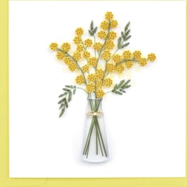 Yellow pom-pom flowers in a clear glass vase with a small bow
