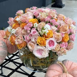 Bouquet of pink, peach, and yellow roses in a glass vase
