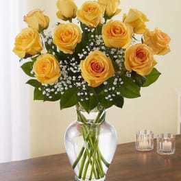 Yellow roses arranged in a clear glass vase with baby's breath.