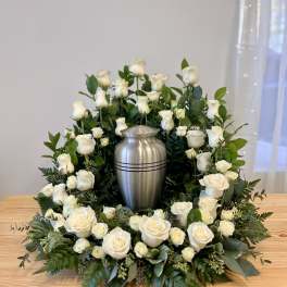 White rose wreath around a silver urn on a table