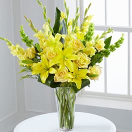 Yellow lilies and roses in a clear glass vase