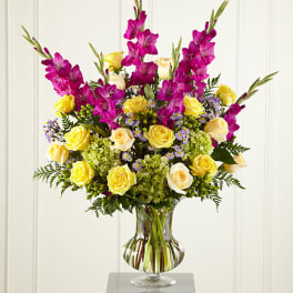 Bouquet of yellow roses and magenta gladiolus in a glass vase