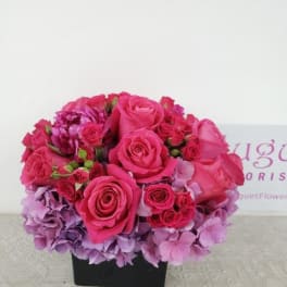 Pink roses and hydrangeas arranged in a black square vase