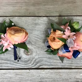 Two small floral boutonnieres with peach blooms and pink accents