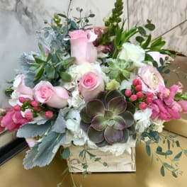 Pink roses and white blooms arranged with succulents in a wooden box