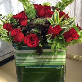 Red roses in a square glass vase with green succulents