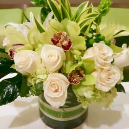 White roses and green orchids in a glass vase
