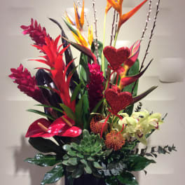 Tall tropical arrangement with red and orange blooms in a black container