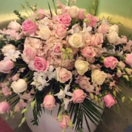 Large pink and white rose arrangement in a white container
