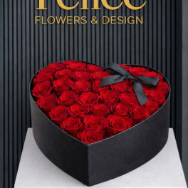 Heart-shaped box filled with red roses and a black ribbon bow