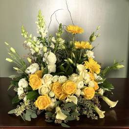 Yellow and white floral arrangement with roses, calla lilies, and daisies