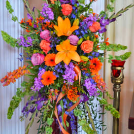 Tall floral standing arrangement with orange, purple, and pink blooms