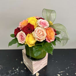 Mixed roses in a green vase with a sheer ribbon bow