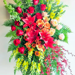 Large standing floral spray with red roses, lilies, and yellow blooms