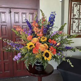 Large colorful floral arrangement in a black vase on a round table