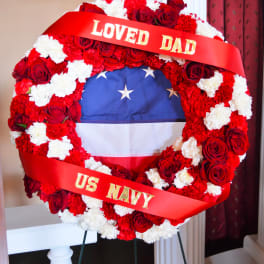 Red and white floral wreath with a ribbon reading "LOVED DAD" and "US NAVY"