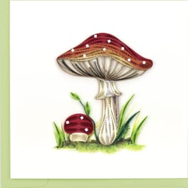 Quilled paper illustration of two red mushrooms with grass on a white greeting card.