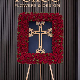 Standing floral cross covered in red roses on an easel