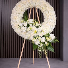 White floral wreath on a wooden easel with a cascading bouquet