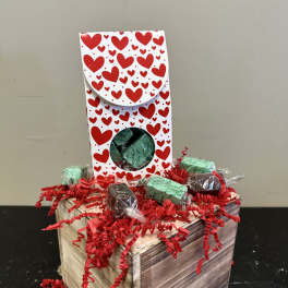 Heart-patterned gift box with wrapped chocolates on a wooden crate