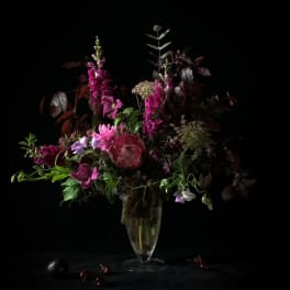 Tall magenta and purple floral arrangement in a clear vase