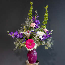Mixed bouquet with a pink gerbera daisy in a purple vase