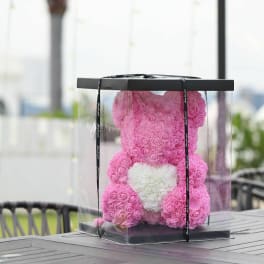 Pink rose teddy bear in a clear gift box with a white heart