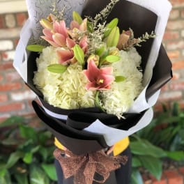 Bouquet of pink lilies and white hydrangeas wrapped in black and white paper