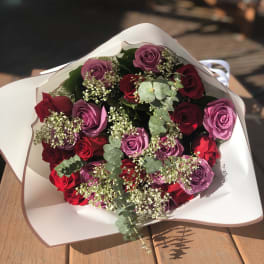 Bouquet of red and purple roses wrapped in white paper