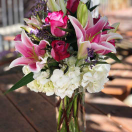 Pink lilies and roses in a clear glass vase with white hydrangeas