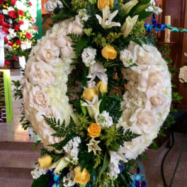 Large floral wreath with white roses, lilies, and yellow accents