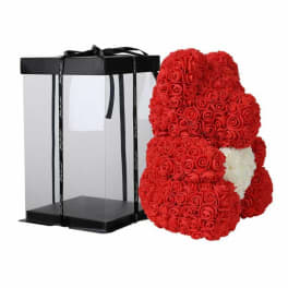 Red rose teddy bear beside a black gift box with ribbon.