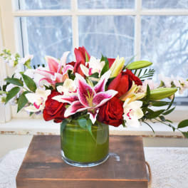 Bouquet of red roses and pink-and-white lilies in a green glass vase