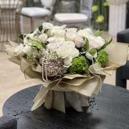 Bouquet of white roses and green hydrangeas with pearl strands in beige wrap