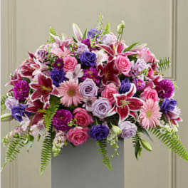 Large pink and purple arrangement with lilies, roses, and gerbera daisies on a pedestal