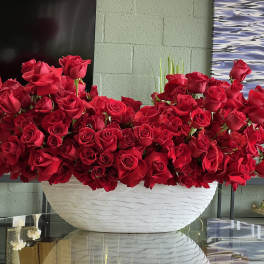 Large arrangement of red roses in a white bowl vase