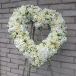 Heart-shaped white floral wreath on a stand