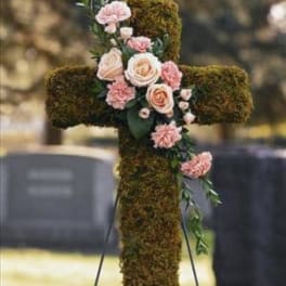 Moss-covered cross with pink flowers on a stand