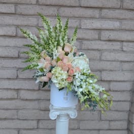 Pastel floral arrangement in a white hatbox on a pedestal