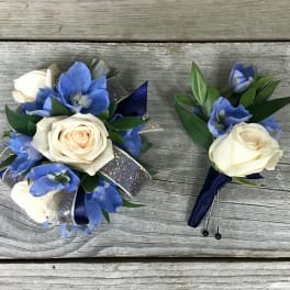 Blue and white floral corsage and boutonniere on a wooden surface