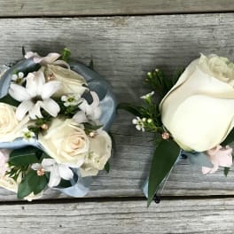 White rose boutonniere and matching floral wrist corsage on a wood surface