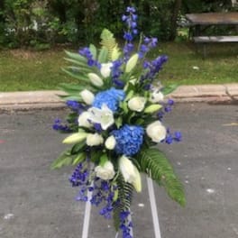 Tall blue and white floral standing arrangement on a white easel