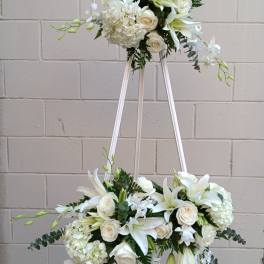 White floral arrangement on a standing easel with roses and lilies
