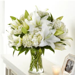White lilies and hydrangeas in a clear glass vase