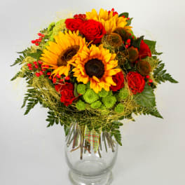 Bright bouquet with sunflowers, red roses, and green mums in a clear glass vase