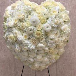 Heart-shaped standing arrangement of white and cream roses and hydrangeas on a metal easel