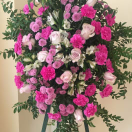 Standing floral spray with pink and white flowers on a tripod easel